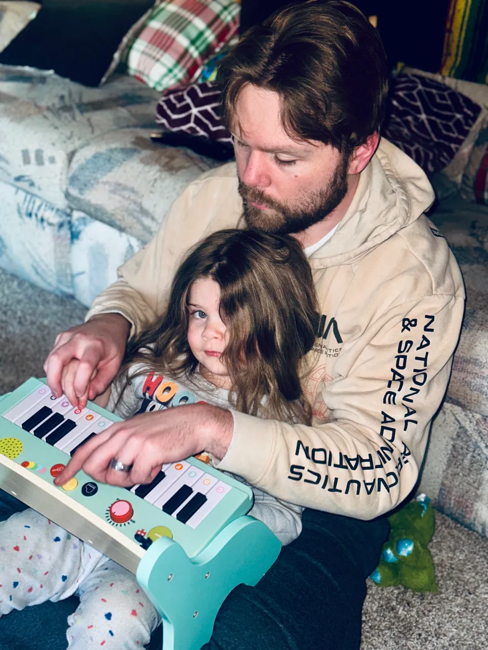 Nathaniel with his daughter playing a toy piano